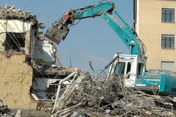 Ein Bagger reißt ein Haus ab.